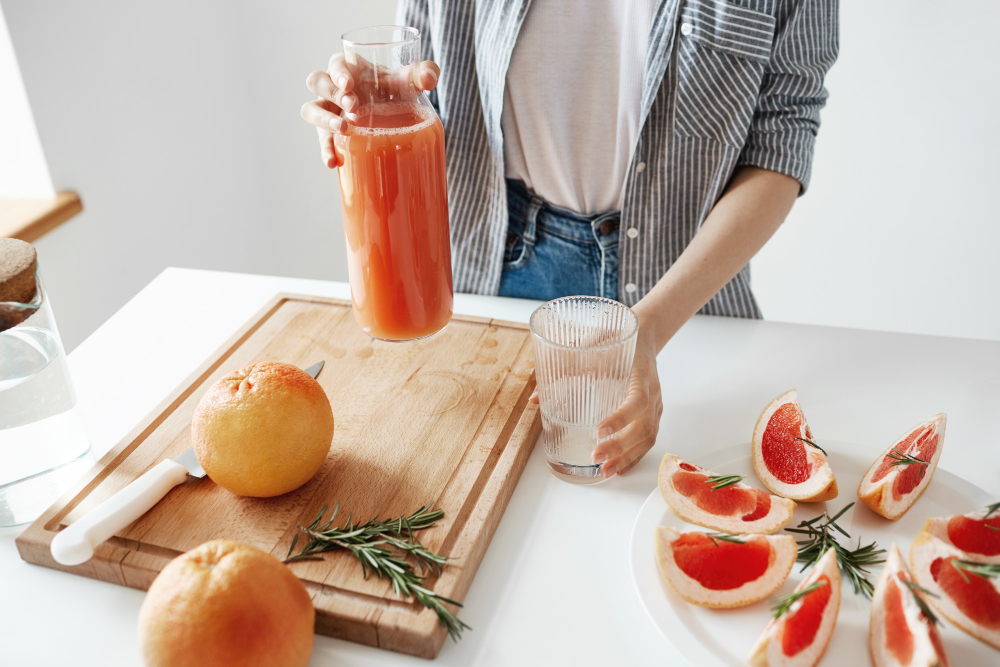 Mujer joven prepara agua de frutas. 
La fotografía muestra un plano bierto en el que solo se ve  del torso hacia abajo de la mujer, quien viste jeans, una camiseta blanca y una camisa desabotonada  a rayas azules y blancas, frente a ella, sobre una mesa blanca, están dispuestos todos los ingredientes para el agua de frutas: toronjas enteras y rebanadas, junto con ramitas de romero. 

También hay una tabla de picar con un cuchillo encima. La mujer sostiene una jarra lena de agua en una mano, y un vaso vacío en la otra.